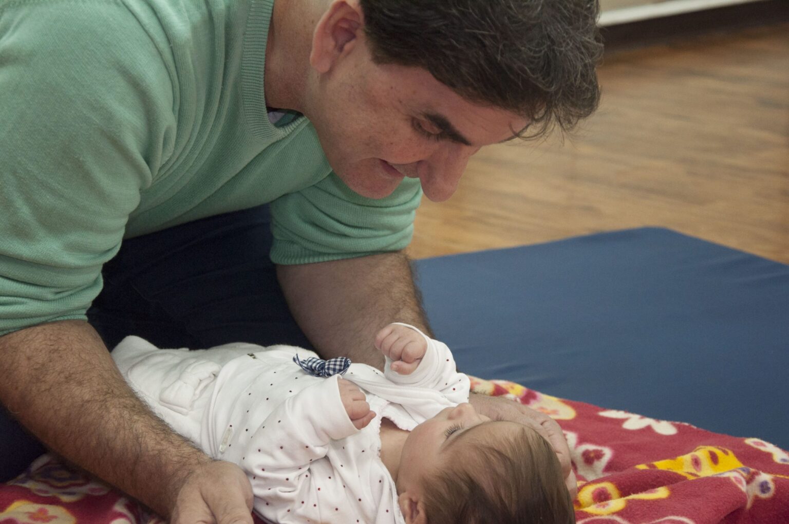 יהודה מלול רוכן מעל תינוק ומתבונן בו